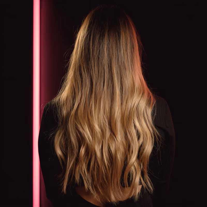 Capelli biondi lunghi con balayage, visti di schiena, onde morbide dalla radice scura alle punte chiare